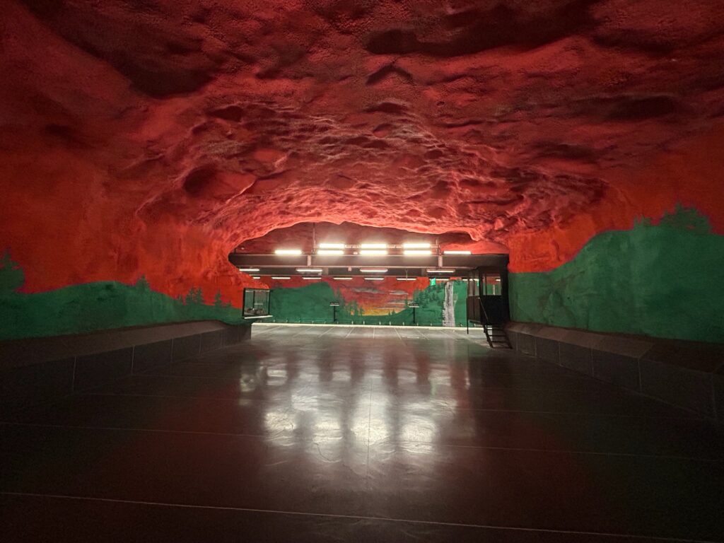 Red ceiling over a painted green forest at Solna Centrum metro station